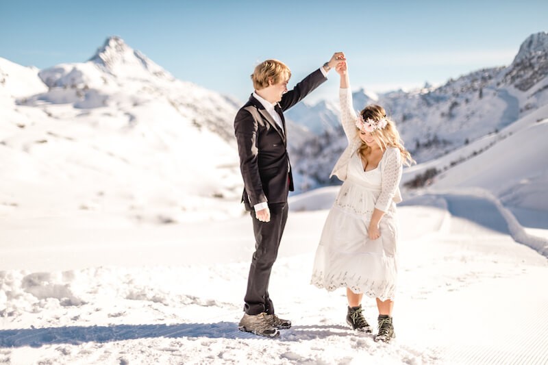 Hochzeitspaar tanzt auf einem Gipfel im Schnee