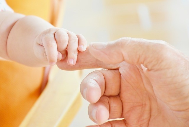 Babyhand mit der Hand vom Papa