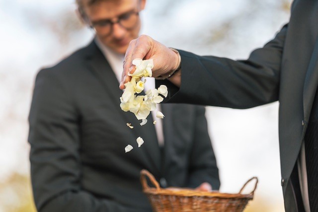 Trauerredner | symbolische Handlung am Grab, Trauergäste werfen weisse Blüten ins Grab