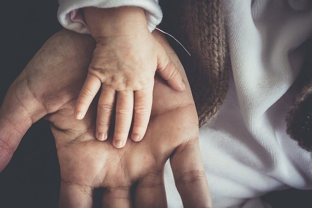Kinderwillkommensfest Baby-Hand in Hand