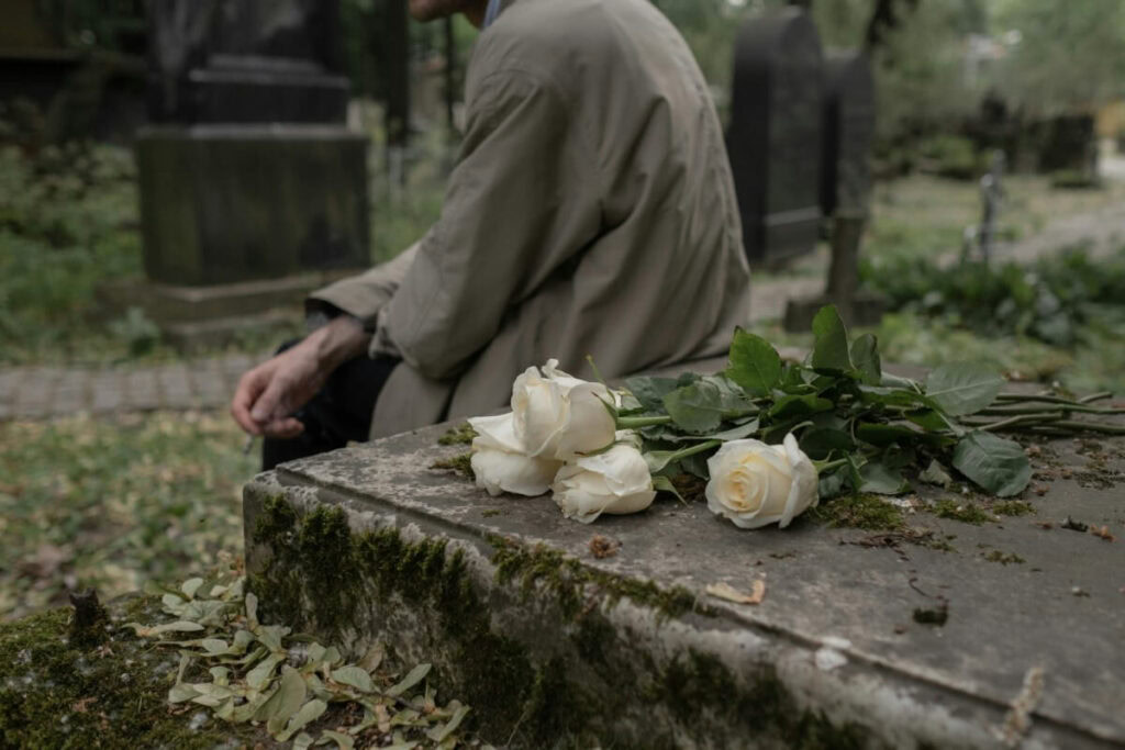 Trauerredner in Villach hält eine einfühlsame Rede bei einer Abschiedszeremonie auf einem Friedhof, umgeben von trauernden Angehörigen.