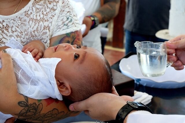 Kinderwillkommensfest | Baby erhält als Ritual Wasser über den Kopf