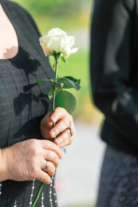 Trauerredner - Eine Frau hält eine weiße Rose in ihrer Hand