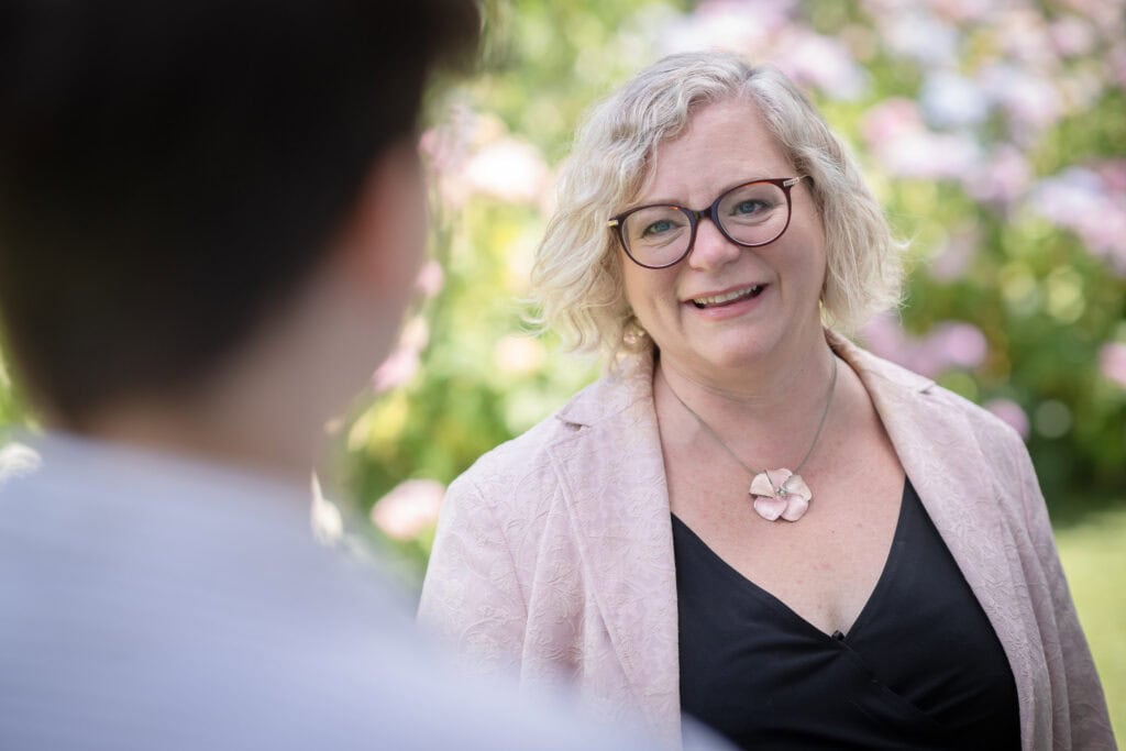 Freie Rednerin Sigrid Sudi aus Österreich im Gespräch mit einem Klienten im Garten.