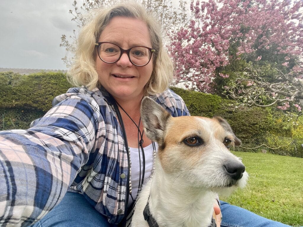 Frau mit Brille und Hund im Grünen, bei blühendem Baum, bei einem öffentlichen Redner-Event in Österreich.