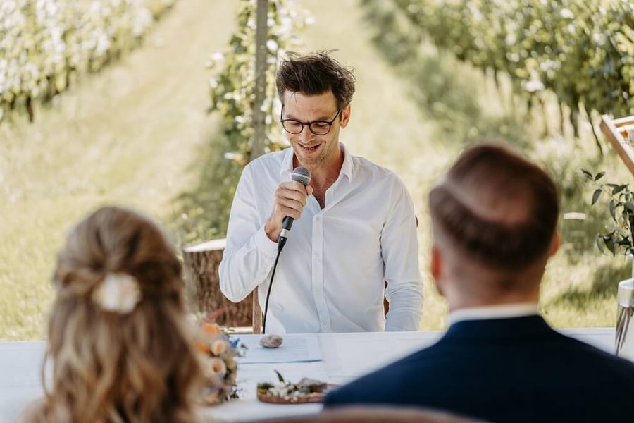 Freier Redner Fabian Schmid | Fabian hält eine Freie Trauung vor dem Brautpaar in einem Weinanbeu